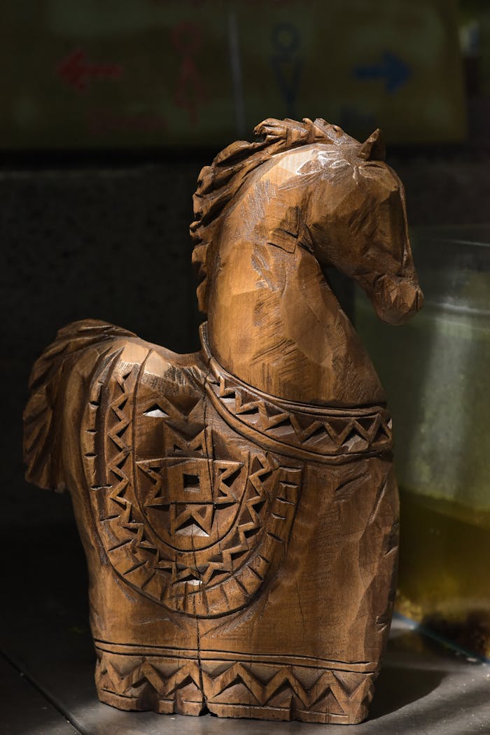Detailed wooden horse sculpture with intricate carvings, captured in a cozy indoor setting.