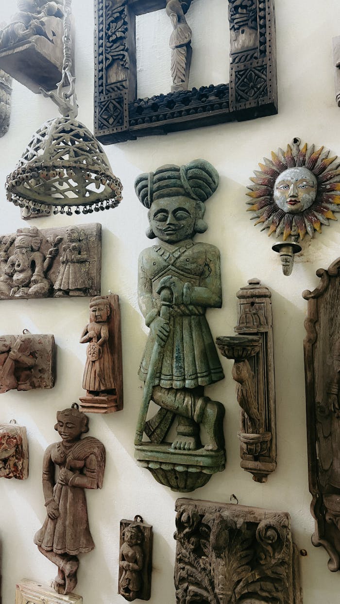 A collection of vintage handcrafted wooden art pieces displayed on a wall, featuring cultural motifs and intricate carvings.